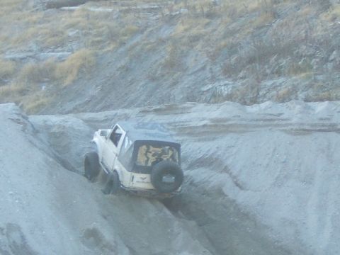 1988 Ford Bronco - A white off-road vehicle navigates a steep dirt incline, its capabilities.
