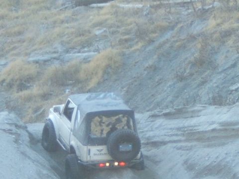 1988 Ford Bronco - Suzuki Samurai navigates a steep, dry, dirt hill with sparse vegetation.