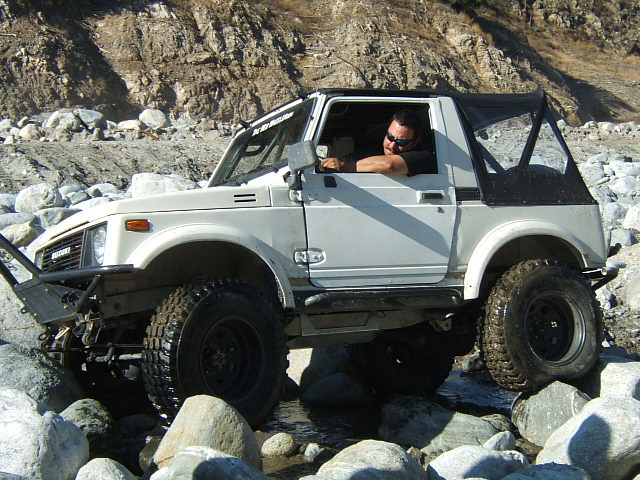 White Suzuki Samurai navigating rocky terrain