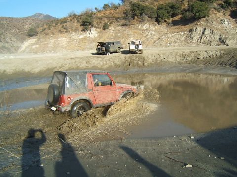 1988 Ford Bronco - An off-road vehicle navigates a muddy obstacle course with other vehicles nearby.
