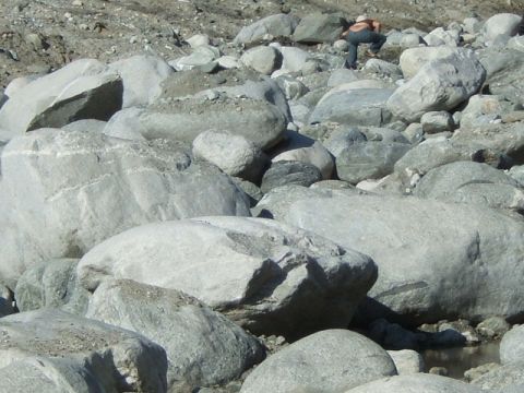 1988 Ford Bronco - A person is seen in the distance, crouching down amidst a landscape of large rocks and debris.