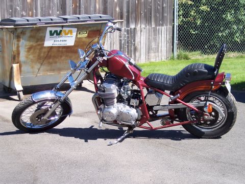 1973 Honda CB750K - Custom motorcycle with a red frame and tank, parked outdoors next to a dumpster.