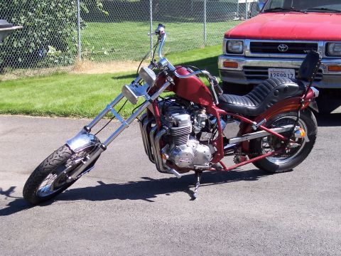 1973 Honda CB750K - A custom chopper motorcycle with extended front forks is parked next to a red pickup truck.