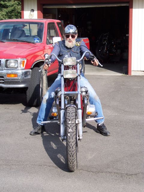1973 Honda CB750K - Man sits on a motorcycle in front of a garage with a red truck parked nearby.