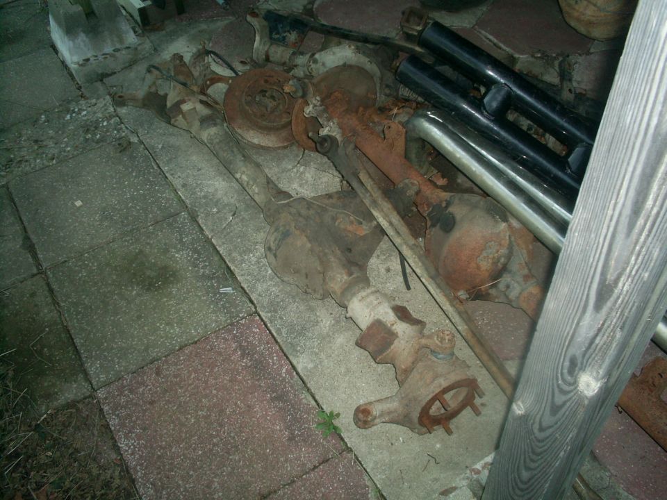 Rusted vehicle axles and suspension parts lying on the ground