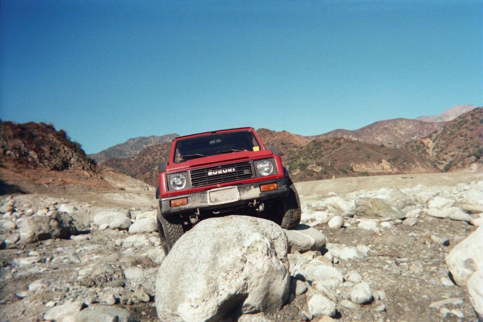 Red 1987 Suzuki Samurai navigating rocky terrain