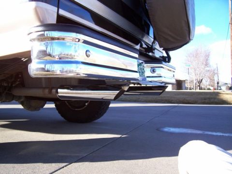 1996 Ford Bronco - Close-up of the rear bumper and exhaust system of a vehicle parked on a driveway.