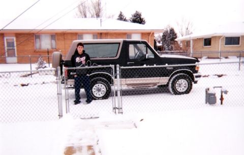 1996 Ford Bronco - A person stands by a black Ford Bronco in a snow-covered residential area.