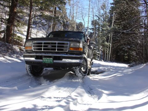 1996 Ford Bronco - A 1995 Ford F-Series truck navigates a snow-covered road through a forest.