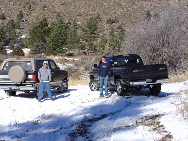 1996 Ford Bronco parked next to a black Dodge Ram pickup truck in the snow