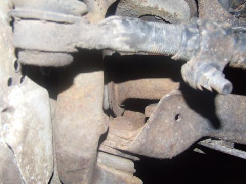 1992 Ford Bronco - This image shows a close-up view of a rusty suspension component, likely part of a vehicle's steering or suspension system.