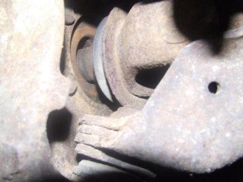 1992 Ford Bronco - A close-up view of a rusty suspension component, showing a metal band and weathered metal.