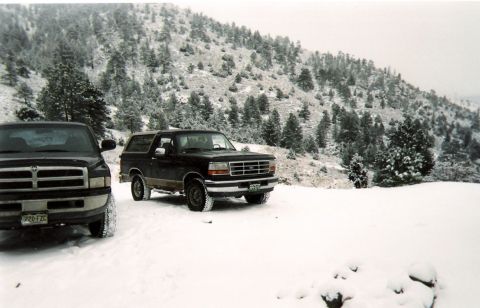 1996 Ford Bronco - A 1996 Ford Bronco is parked in the snow next to another vehicle, with a wooded hillside in the background.