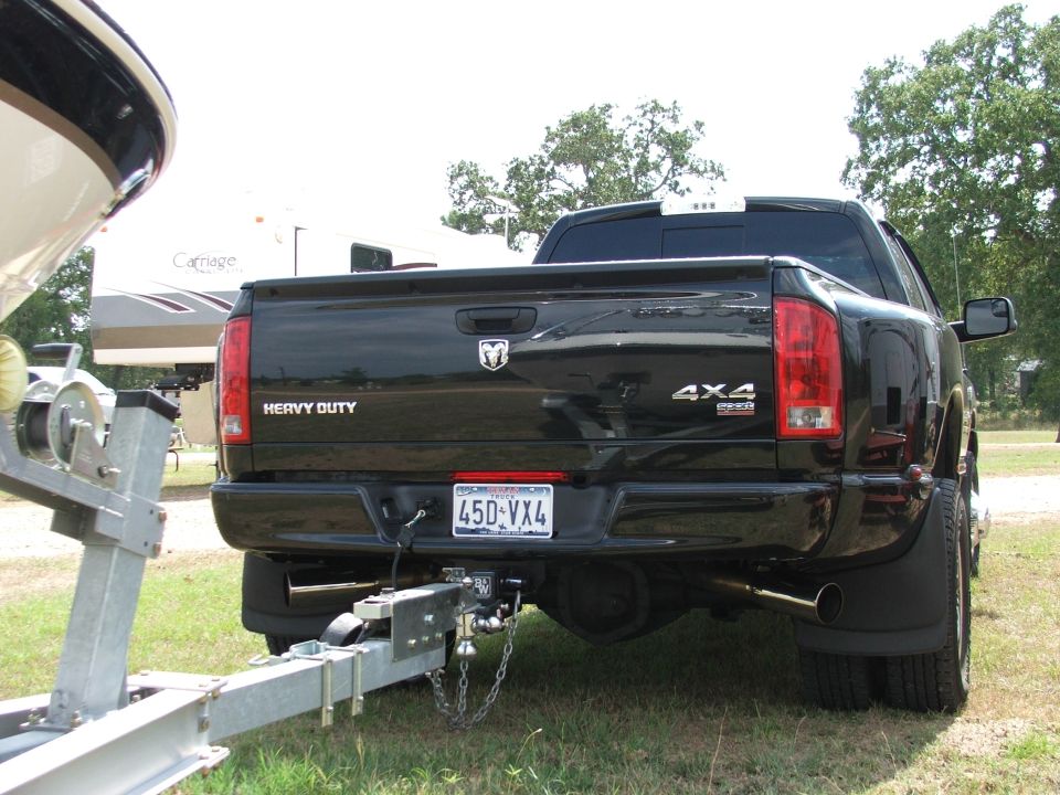 Black Dodge Ram dually pickup rear view towing a boat trailer with Texas plate.