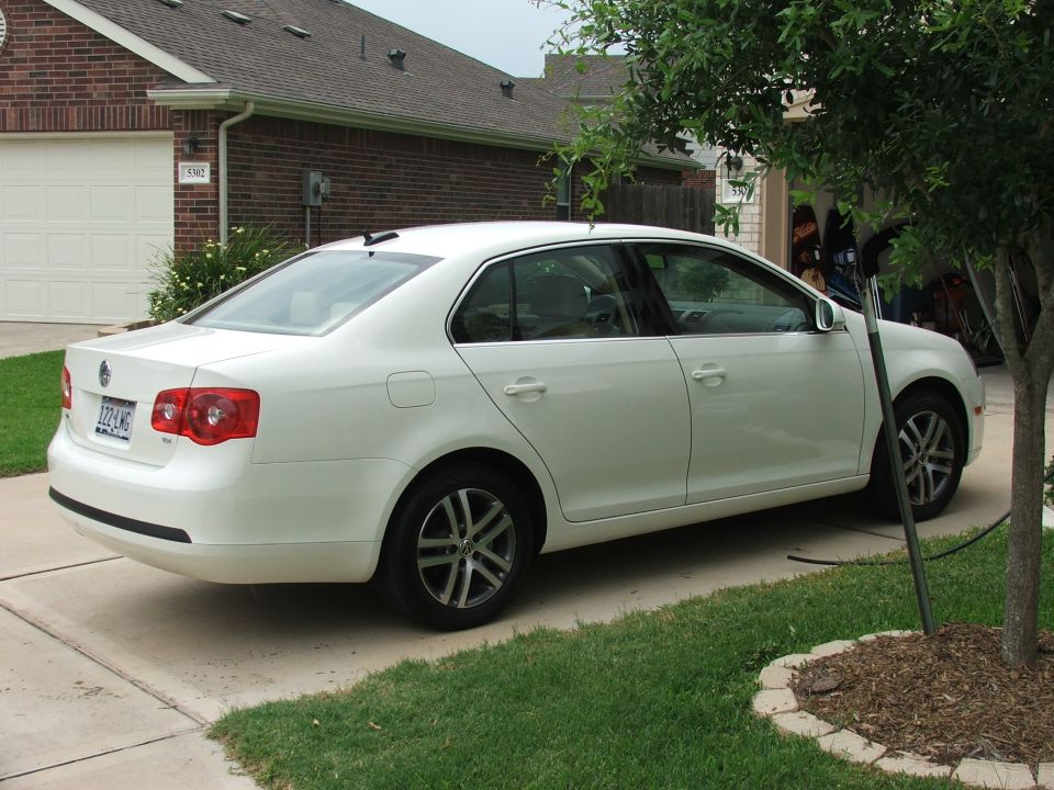 White Volkswagen Jetta sedan parked in a driveway, rear side view