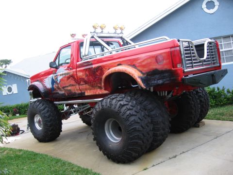 1974 Ford F-100 - This heavily modified pickup truck features custom mural artwork and oversized tires, suggesting it is not a standard 1974 Ford F-100.