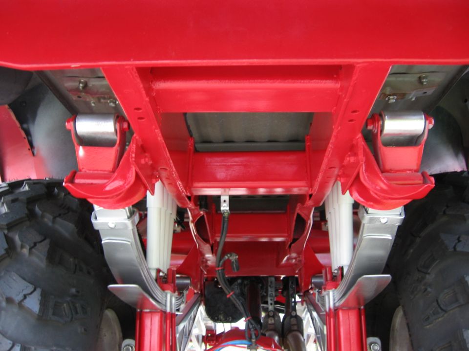 Underside of a red truck frame with leaf springs and shocks visible