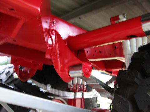 1974 Ford F-100 - Close-up view of the undercarriage of a red painted truck, highlighting the suspension and frame.