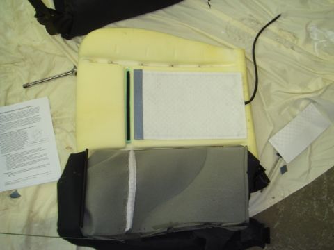 1996 Ford Bronco - A car seat cushion, disassembled to reveal its internal heating element and foam structure, lies next to a technical document.