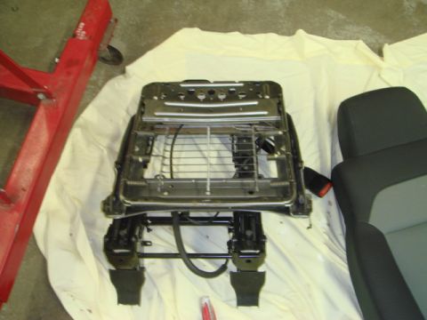 1996 Ford Bronco - Disassembled car seat frame and upholstery shown on a white cloth, with a red stand in the background.