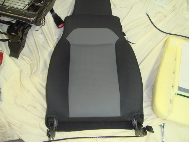 Car seat with black and gray fabric, detached from its frame. Foam padding is visible to the right