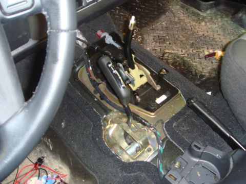 1996 Ford Bronco - Exposed transmission shifter and wiring in a vehicle's center console.