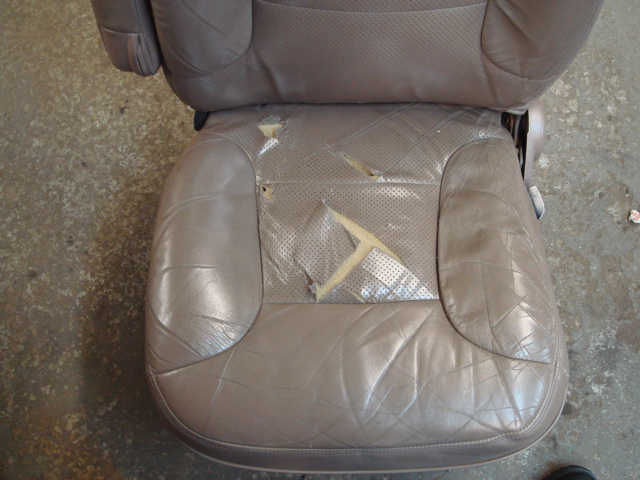 Torn leather car seat with visible foam padding underneath