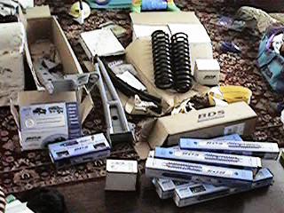 1986 Ford Bronco - Various automotive parts are laid out on a carpeted floor, suggesting a project or installation.