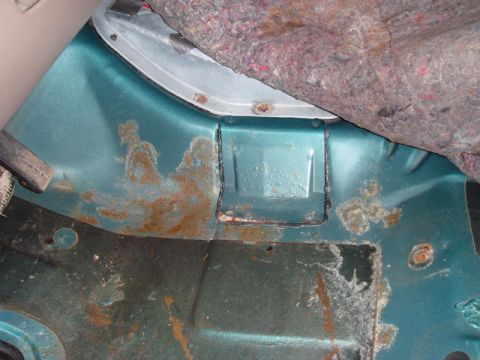 1996 Ford Bronco - The rear cargo area of a vehicle shows significant rust damage and exposed carpet padding.