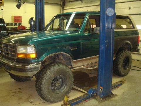 1996 Ford Bronco - This green Ford Bronco is shown on a hydraulic lift in a garage, possibly undergoing maintenance or inspection.