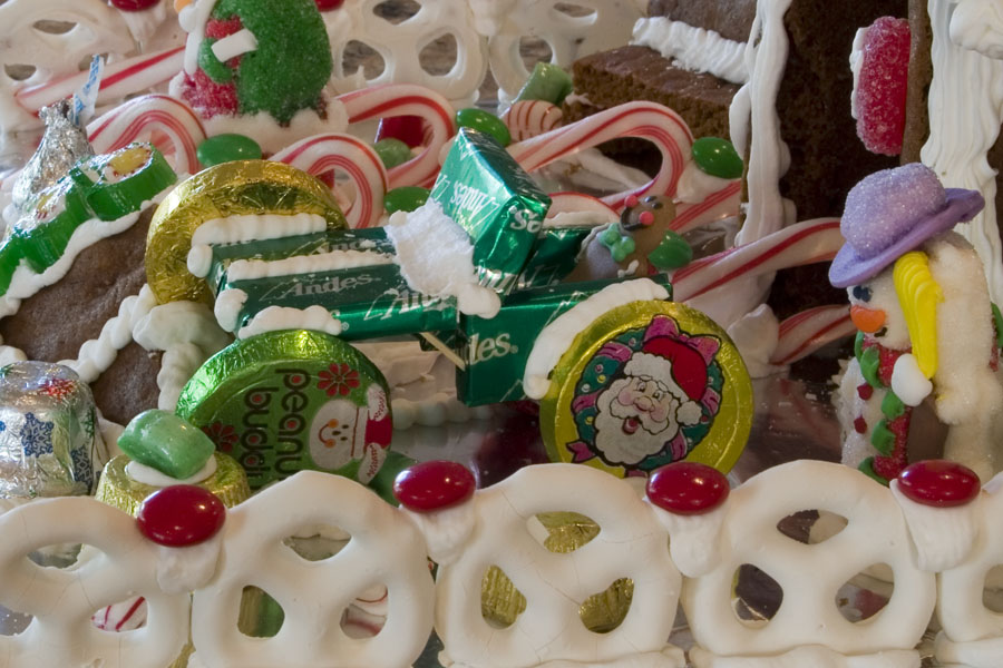 Gingerbread house decorated with candy canes, chocolates, and a snowman figure