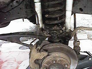 1986 Ford Bronco - Close-up of a vehicle's front suspension system, showing a coil spring and brake assembly.
