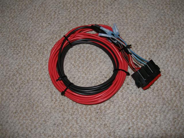 Coiled red and black wiring harness with connector on tan carpet