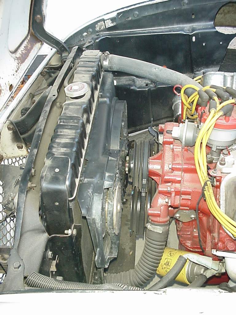Engine bay showing radiator, fan, and red engine block with yellow spark plug wires