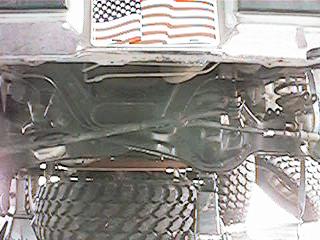 1986 Ford Bronco - This image shows the underside of a vehicle, focusing on the suspension and spare tire. Two stickers are visible at the top of the frame.