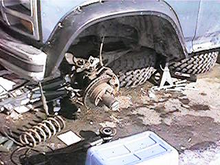 1986 Ford Bronco - Close-up of a lifted Ford Bronco's front suspension system, showing the wheel hub and brake components.