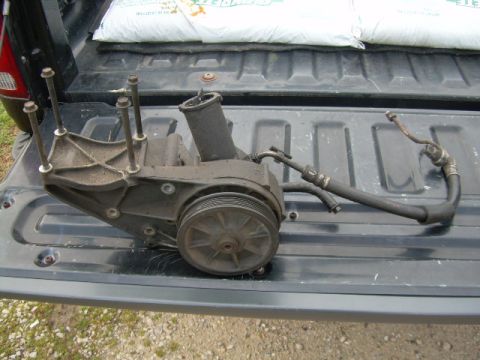 1992 Ford Bronco - Power steering pump assembly, removed from vehicle, resting on a truck bed.