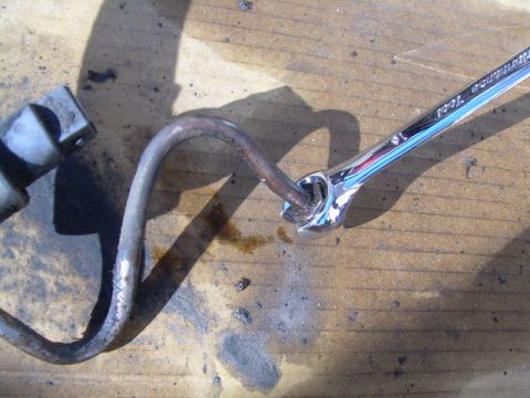 1992 Ford Bronco - Using a 16mm wrench to adjust a metal tube, likely part of a vehicle's fluid system.