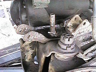 1986 Ford Bronco - This image shows a close-up view of the suspension system of a vehicle, with visible mechanical components and a watermark.