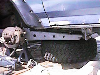 1986 Ford Bronco - Close-up view of the suspension and frame of a 1986 Ford Bronco undergoing modifications.