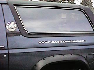 1986 Ford Bronco - Side view of a 1986 Ford Bronco showing the rear quarter panel and a website decal.