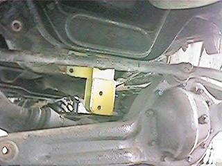 1986 Ford Bronco - Undercarriage view of a yellow suspension part installed on a vehicle.