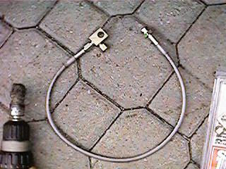 1986 Ford Bronco - Close-up of a brake line assembly with metal fittings.