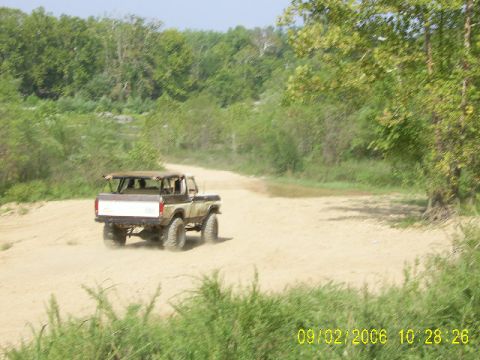 1979 Ford Bronco - Ford Bronco driving on a dirt road through a wooded area.
