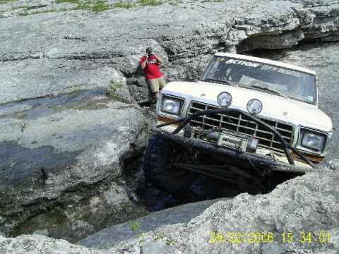 1979 Ford Bronco - White Ford Bronco navigating a difficult rocky obstacle course. 'ACTION OFF ROAD' sticker visible.