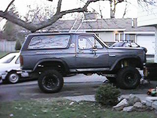 1986 Ford Bronco - Side view of a lifted 1980s Ford Bronco in a residential driveway.