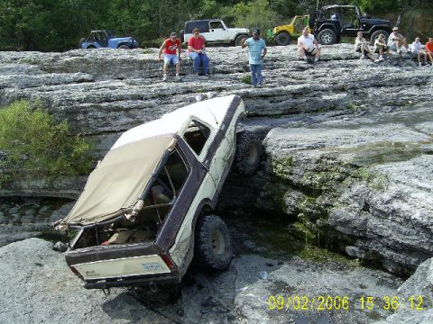 1979 Ford Bronco - This 1979 Ford Bronco is attempting to traverse a difficult rocky obstacle with spectators observing.