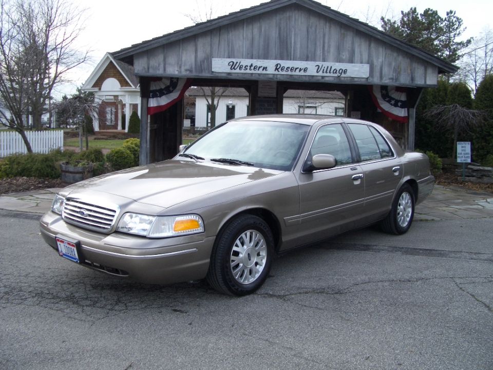 Gold Ford Crown Victoria sedan parked in front of Western Reserve Village sign