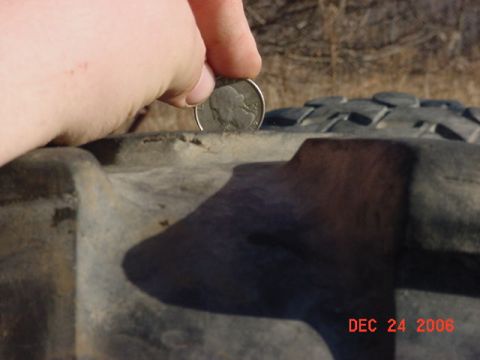 1977 Ford F-250 - A coin is used to measure the tread depth of a tire, indicating wear.