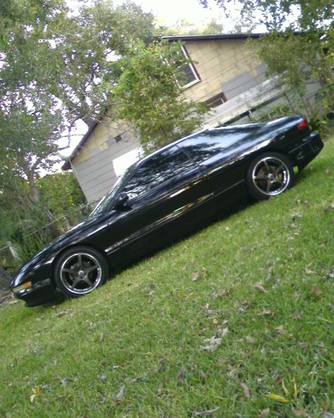 1996 Ford Probe - A black coupe with custom wheels sits on a lawn in front of a house.